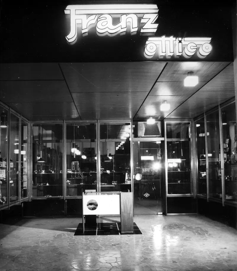 Ingresso del negozio Franz illuminato di sera nel 1965, con l'insegna Franz ottico