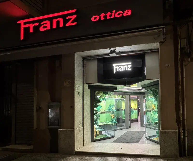 Il negozio Franz Ottica di sera, con l'insegna Franz ottica sulla facciata